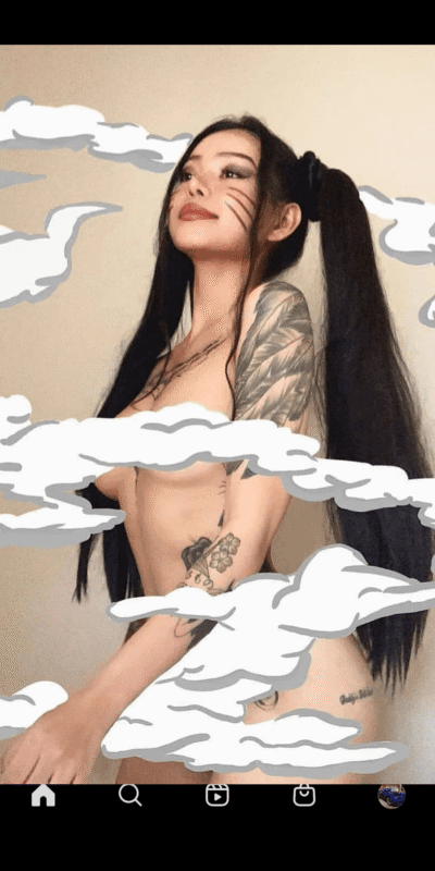 Topless young woman with long black hair and tattoos, posed sideways and looking up, with white cloud overlays across the image.