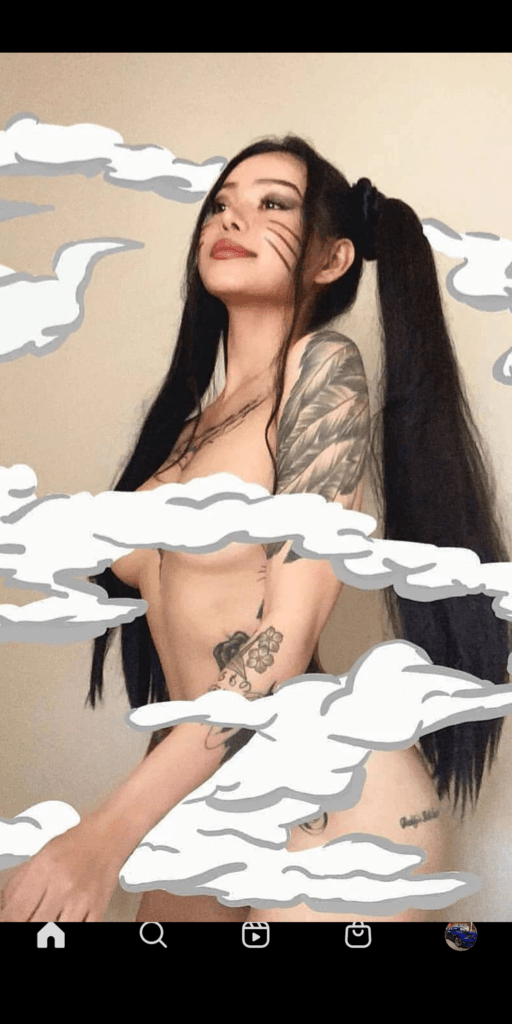 Topless young woman with long black hair and tattoos, posed sideways and looking up, with white cloud overlays across the image.
